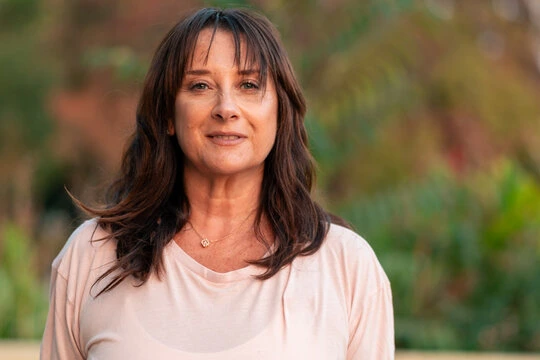 Headshot of a smiling brunette adult woman outdoors, illustrating daily productivity and cognitive performance.
