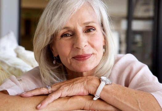 Close-up of a smiling senior blonde woman with a watch, showcasing long-term brain health and lifestyle confidence.