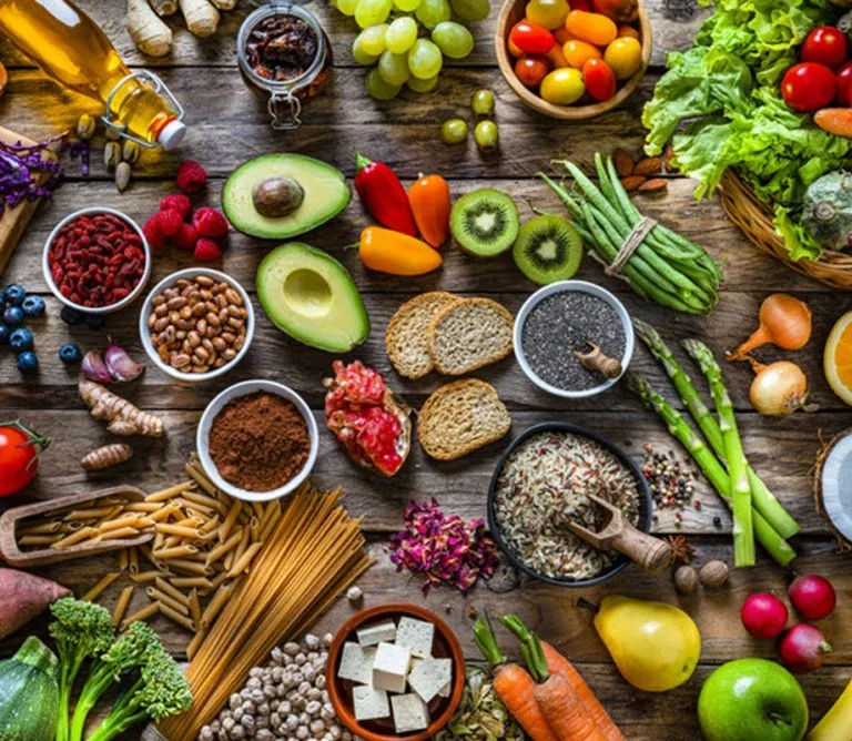 Fresh salmon fillets, avocado, nuts, and green vegetables arranged on a table, illustrating a diet rich in healthy fats and nerve vitamins.