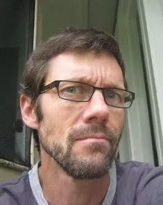Headshot portrait of a middle-aged man with glasses, representing organic consumer feedback and satisfaction with energy levels.