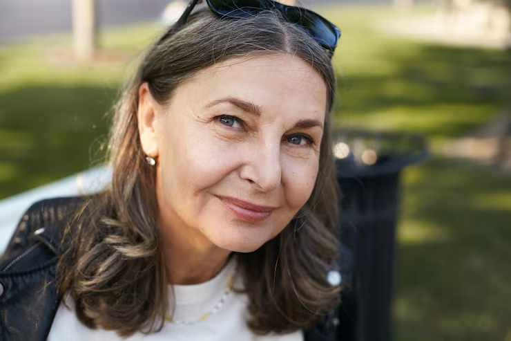 Headshot of a smiling middle-aged brunette woman outdoors, illustrating restored daily physical comfort and mobility.